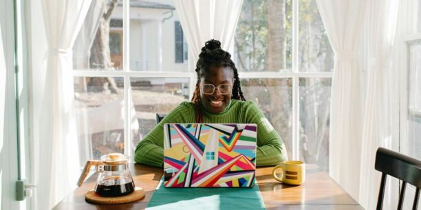 Woman in green sitting at kitchen table sending year-end thank you messages