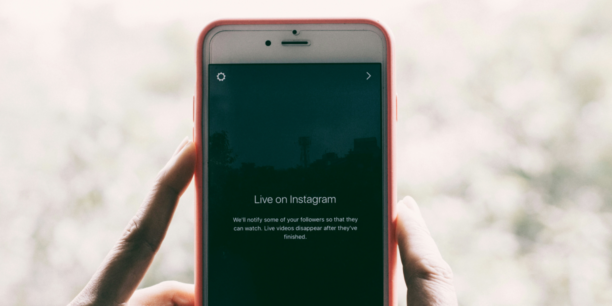 Someone holding their cell phone up to display the Instagram platform