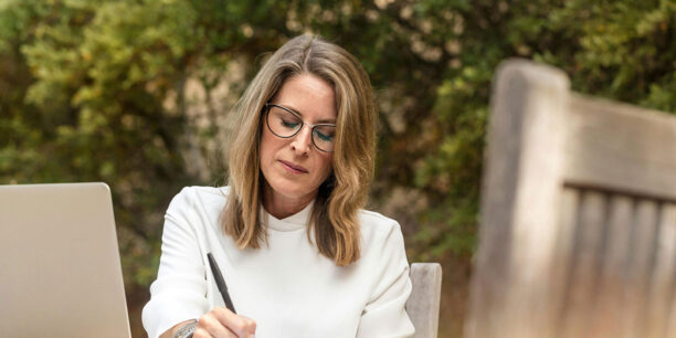 Woman in white sweater researching donation page examples on her laptop