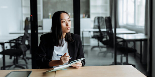 Woman in black blazer writing donor retention strategies in her notebook